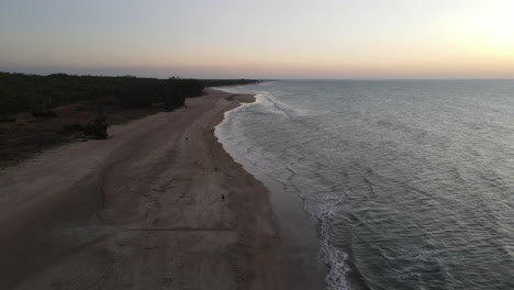 Toma-De-Drones-En-Movimiento-Lento-De-Puesta-De-Sol-Naranja-Y-Gente-Caminando-En-La-Playa-De-Lee-Point-En-Darwin,-Territorio-Del-Norte