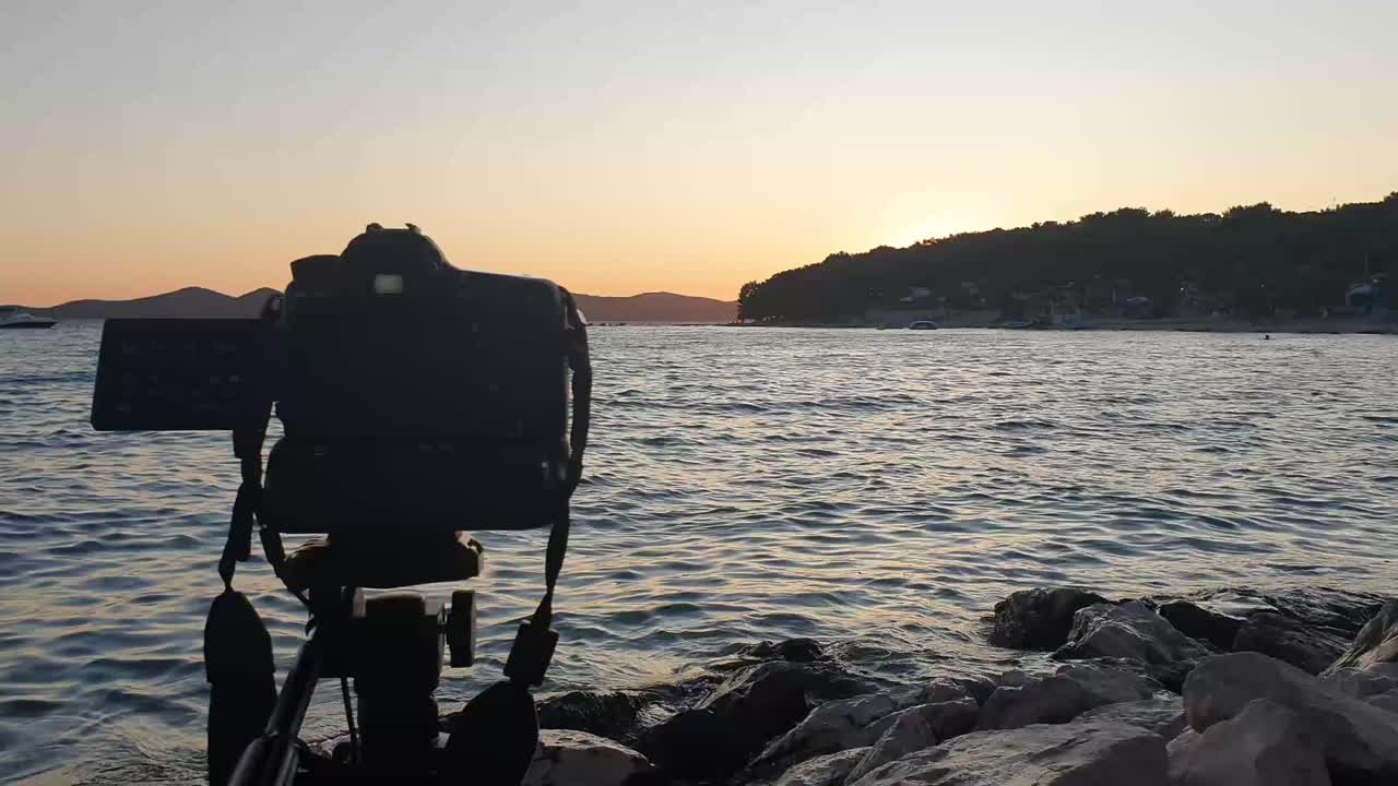 cámara de pie sobre un trípode oscuro disparando timelaps al atardecer