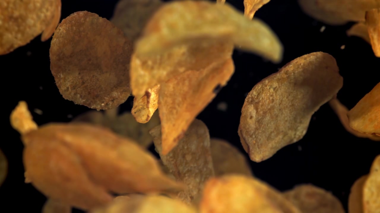 Potato Chips Falling in Slow Motion on Black Background