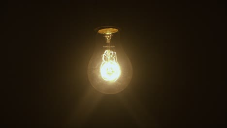Antique-light-bulb-glowing-on-a-black-dark-background,-incandescent-filament,-hipster-decoration