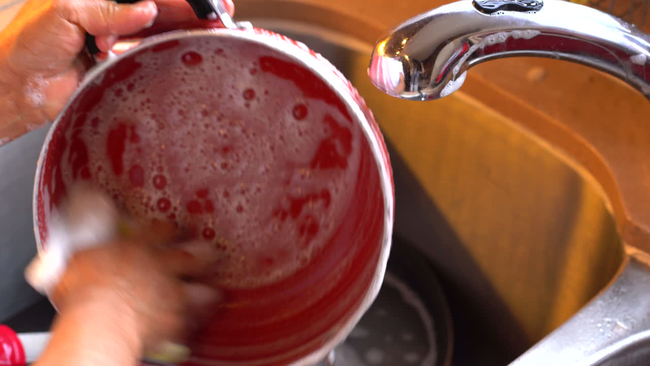 Latin woman washing cooking pot at home
