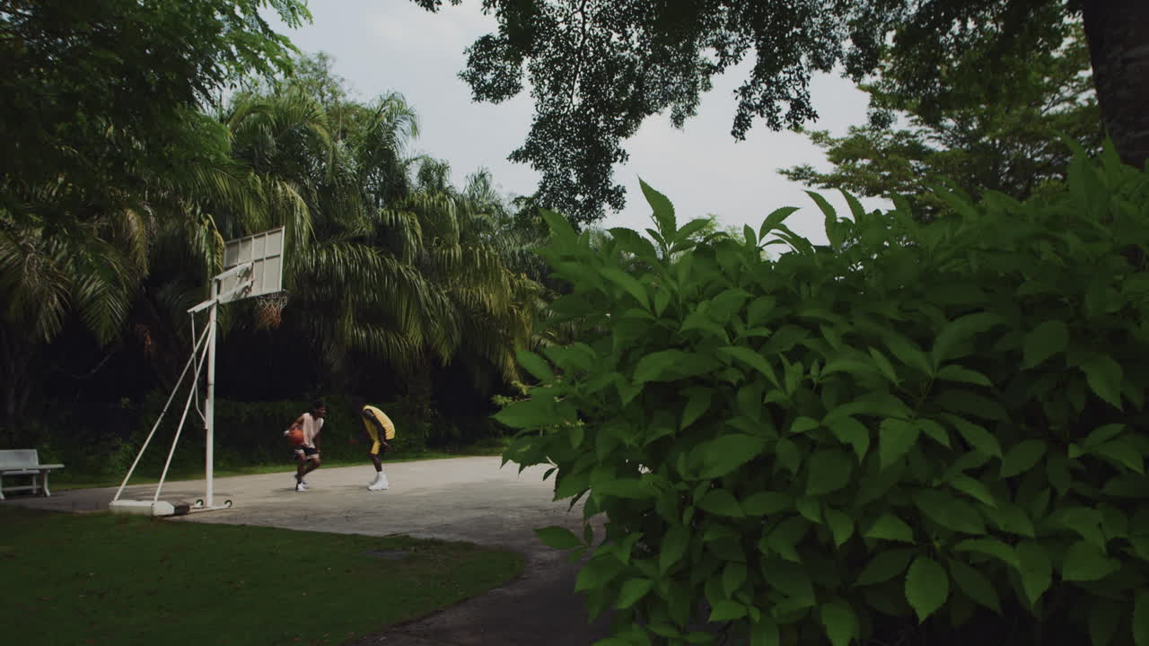 Two Athletes Playing Basketball on Court in Park