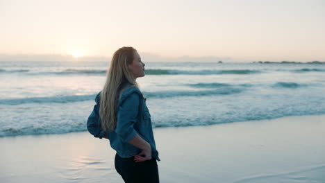 young woman alone on beach looking at sunset on ocean horizon thinking of journey contemplating life enjoying peaceful summer vacation freedom