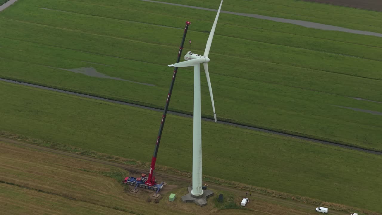 Tecnici e una gru che eseguono la manutenzione di una turbina eolica nella campagna tedesca.