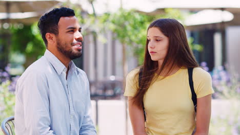 Female-High-School-Student-Talking-To-Teacher-Outside-College-Buildings