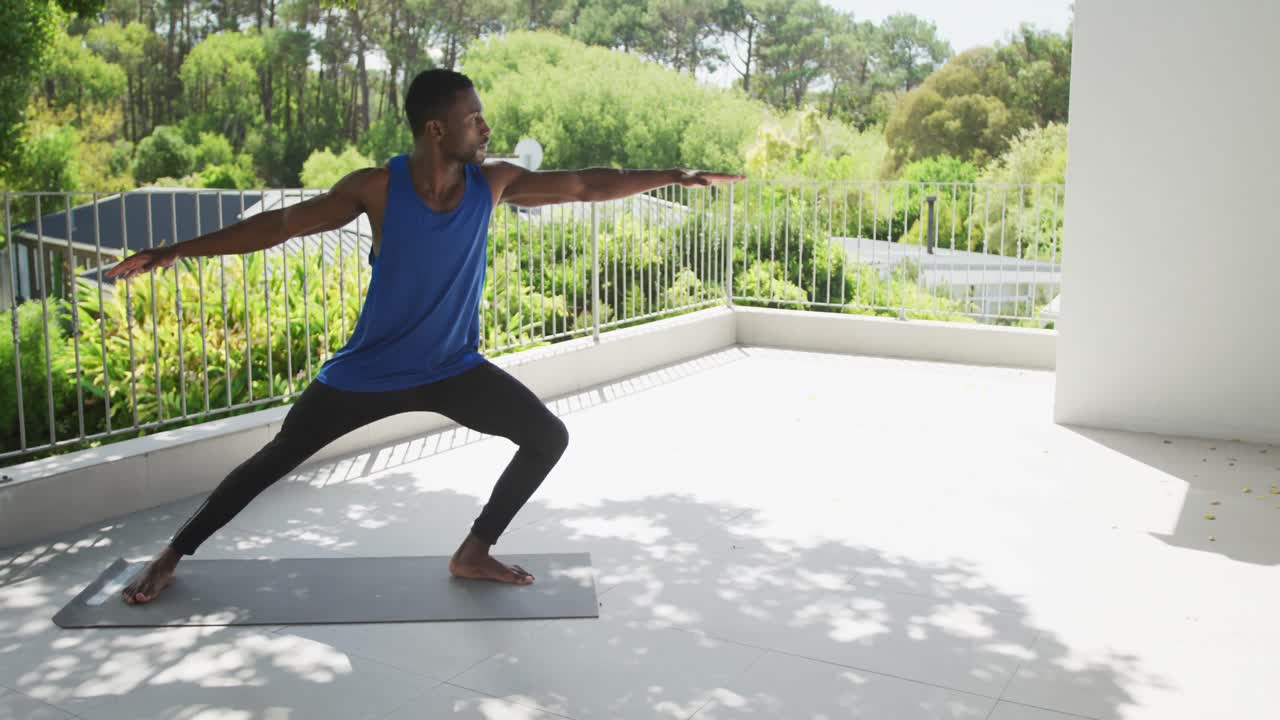 African american man practicing yoga exercising on sunny garden terrace