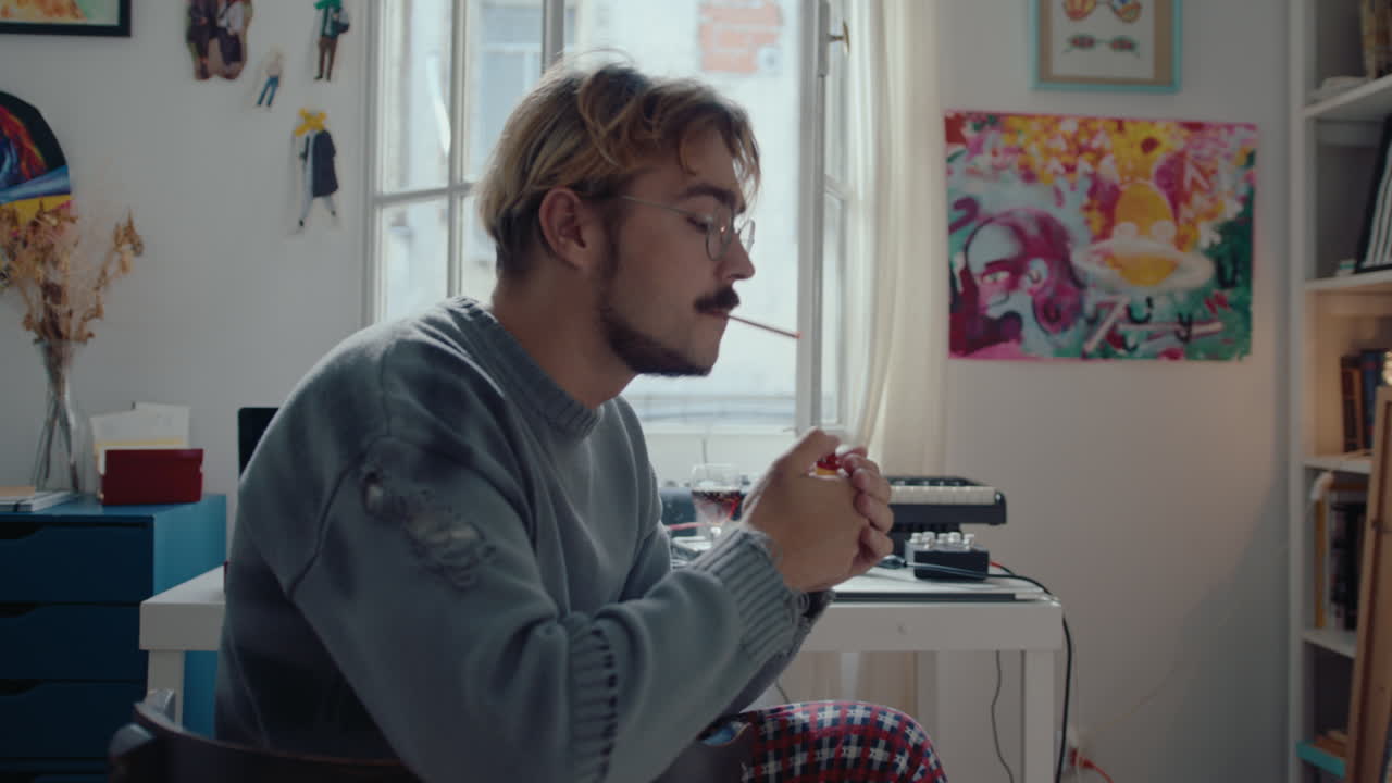 Uomo che fuma una sigaretta prima di registrare musica a casa.