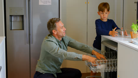 side view of caucasian father and son arranging utensils in kitchen cabinets at comfortable home 4k