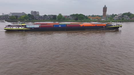 cargo ship with containers on a river passing urban landscape