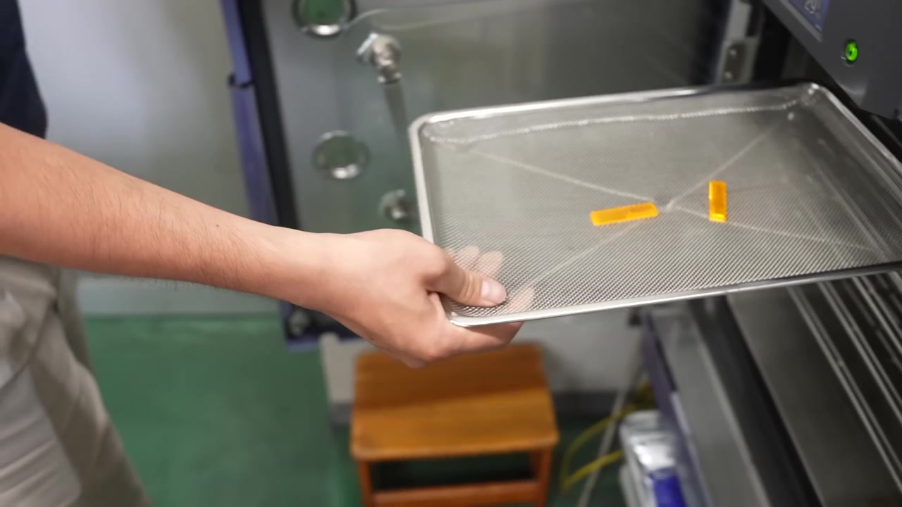 Operaio che posiziona un vassoio di componenti in un forno di prova ambientale per il controllo qualità