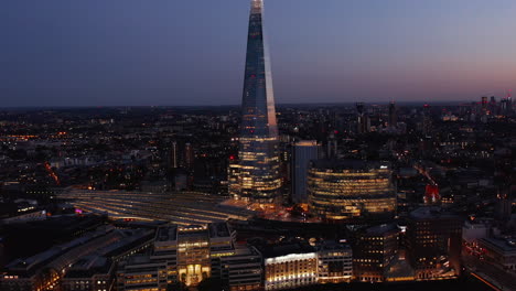 Vista-Aérea-Nocturna-De-La-Estación-De-Tren-Del-Puente-De-Londres-Y-Los-Edificios-De-Oficinas-Circundantes-Después-Del-Atardecer.-Luces-De-La-Ciudad-En-Las-Calles.-Londres,-Reino-Unido