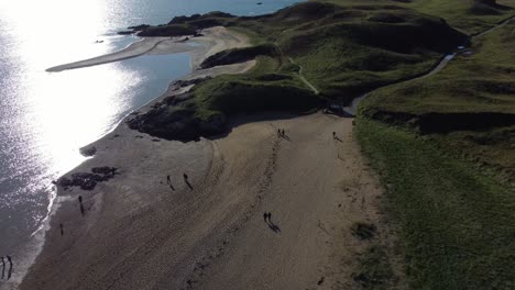 aerial view ynys llanddwyn beach establishing welsh island with shimmering ocean and misty snowdonia mountain range across the sunrise skyline