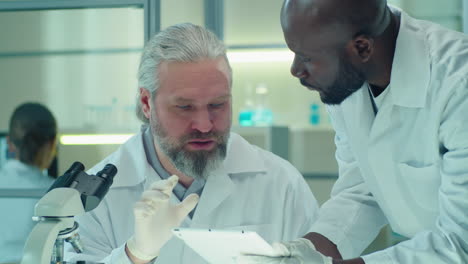 multiethnic lab scientist discussing something on tablet