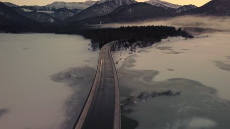 sylvenstein fresh drinking water reservoir bridge in the scenic bavarian austrian alps in snow winter with mountains and clear blue water by sunset