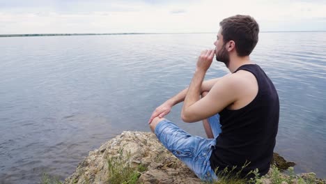 man sitting on a rock by the lake