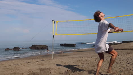 man kicking ball on the beach.