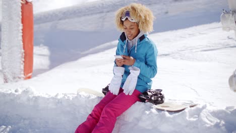 mujer sentada en el banco de nieve enviando mensajes de texto