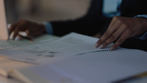 close up business woman hands paging documents reading information on project report working late in office at night