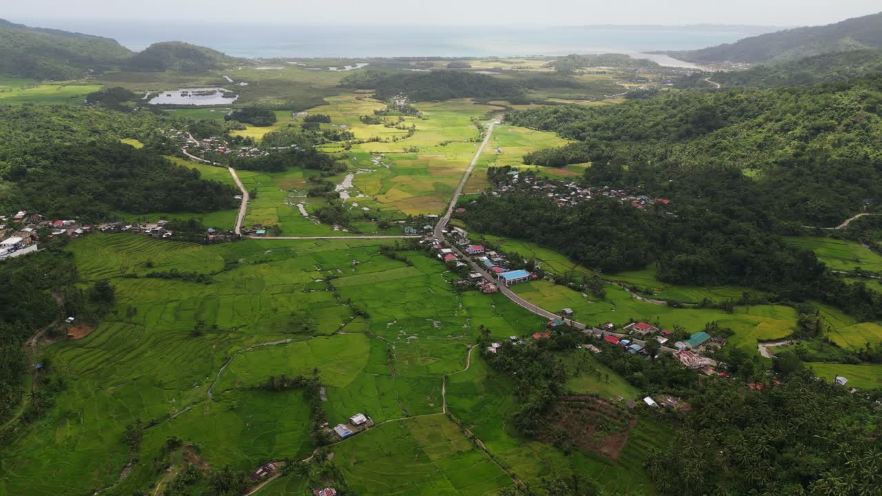 Aerial overview of panoramic lush rural countryside with quaint villages, roads, and tropical jungles at Bagumbayan, Bato, Catanduanes.