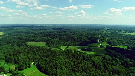 Aerial-view-over-Lush-green-fields-and-forested