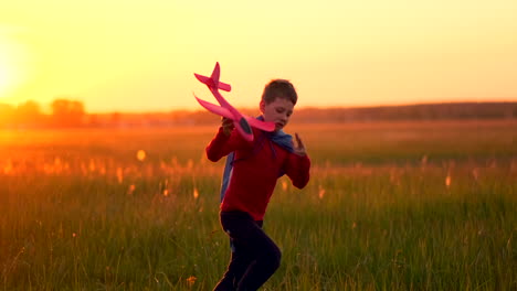 The-boy-in-the-costume-of-a-super-hero-running-in-a-red-cloak-laughing-at-sunset-in-summer-field-representing-that-he-was-the-pilot-of-the-plane