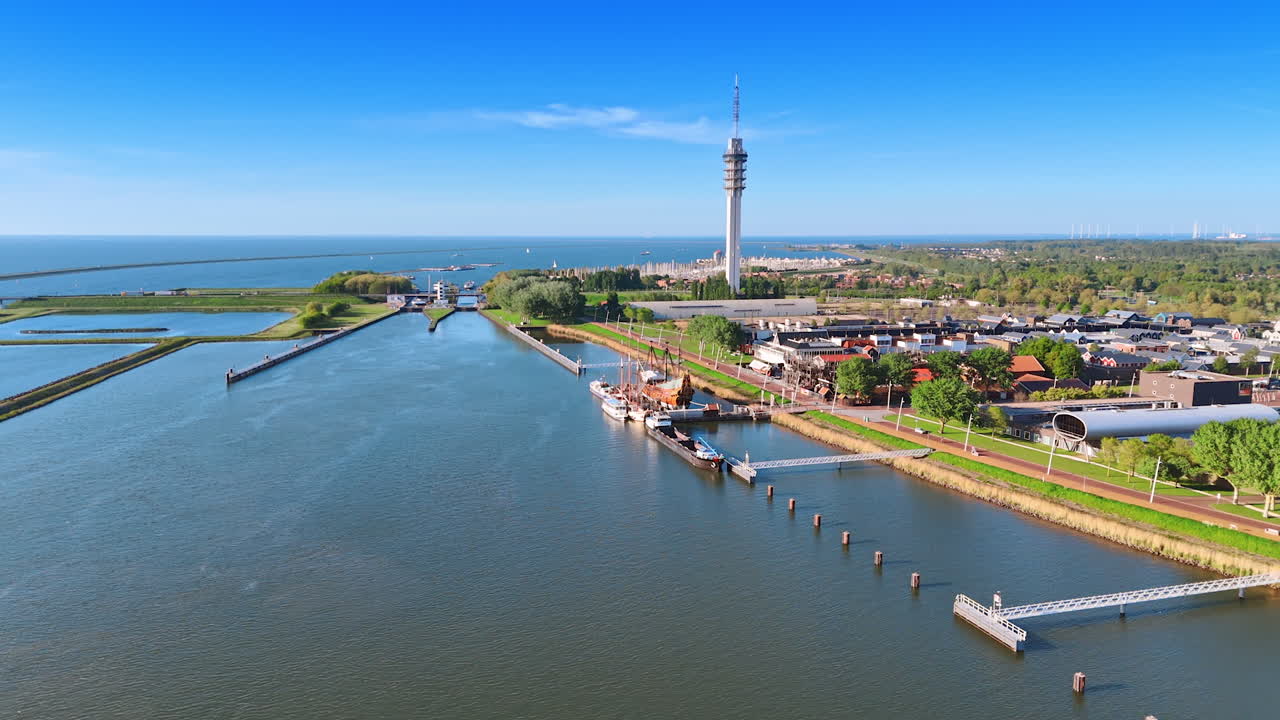 17-century ship reconstruction at the berth of the Historical Museum Batavialand in Lelystad, the Netherlands. Aerial perspective on the green city, telecom tower and dikes.