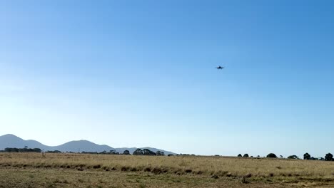 a hawker sea fury aircraft flies across a clear blue sky over geelong, captured in bright daylight with distant mountains