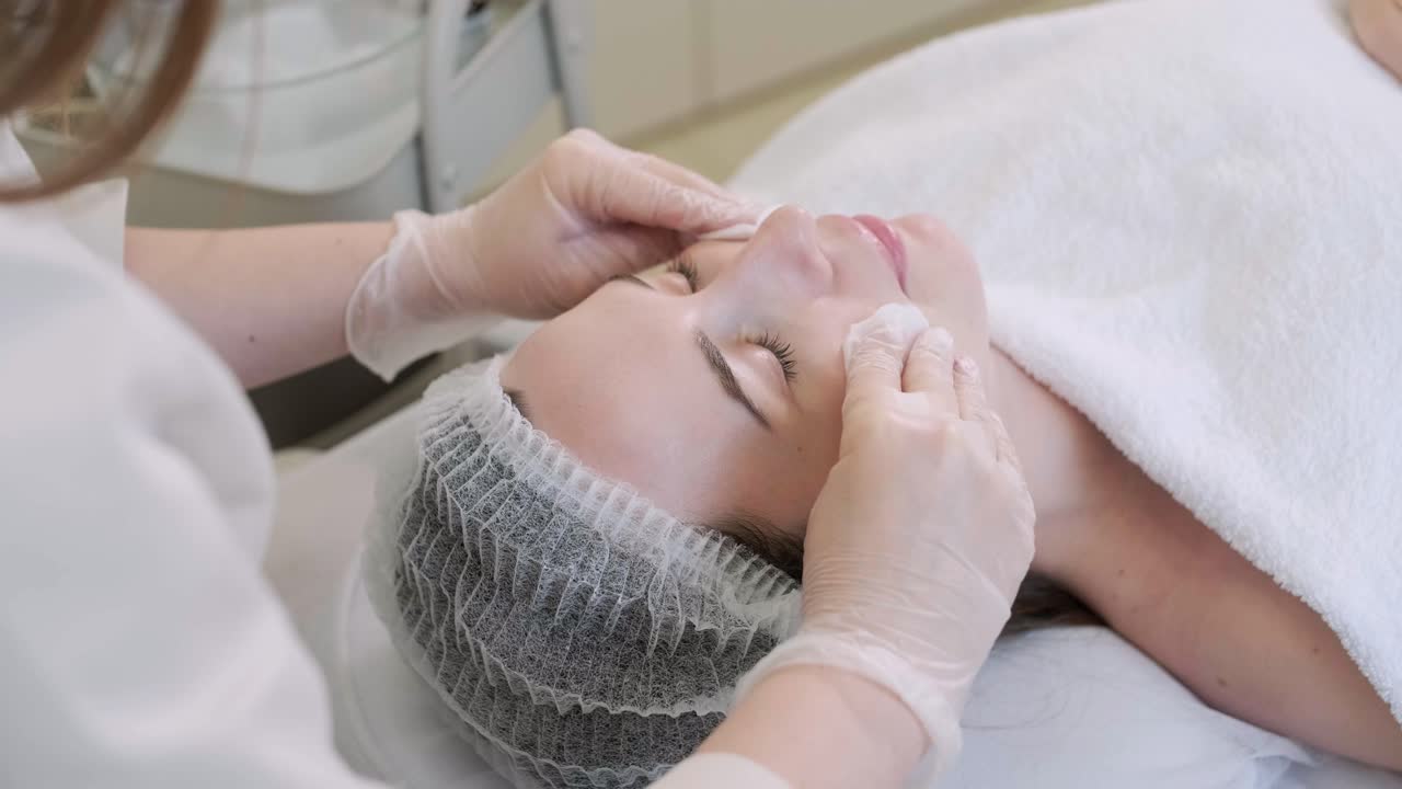 Maschera peeling viso, trattamento di bellezza spa, cura della pelle. Donna che ottiene la cura del viso dall'estetista al salone spa, vista laterale, primo piano