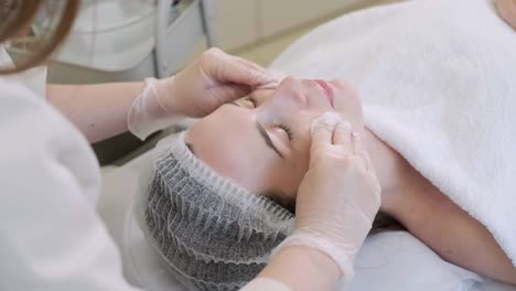 face peeling mask, spa beauty treatment, skincare. woman getting facial care by beautician at spa salon, side view, close-up