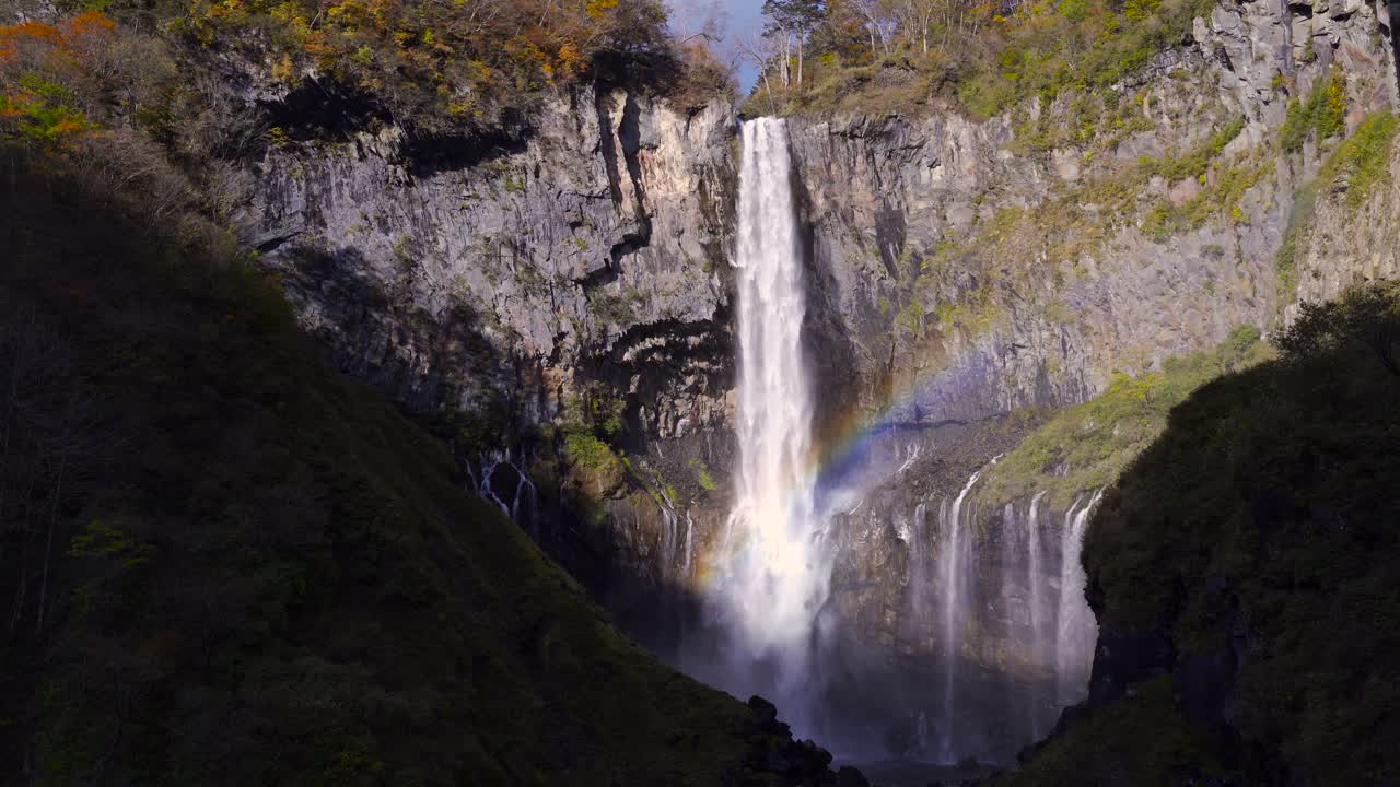 impresionante cascada cayendo entre rocas altas con formación de arco iris
