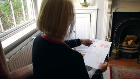 an unrecognizable senior woman worried about debts opening a debt letter