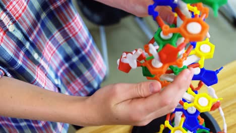 schoolboy experimenting molecule model in laboratory at school