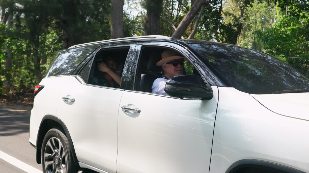 4k 아시아 고령 남자가 해변 로드 트립에서 가족과 이야기하면서 차를 운전합니다.