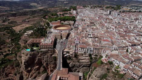 Toma-Panorámica-Aérea-De-La-Plaza-De-Toros-Y-El-Puente-Del-Desfiladero-Del-Tajo-En-Ronda,-Andalucía,-España