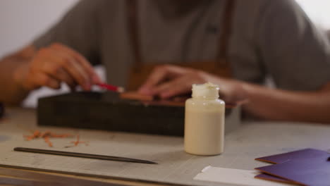 worker applies glue from bottle onto leathers detail edge