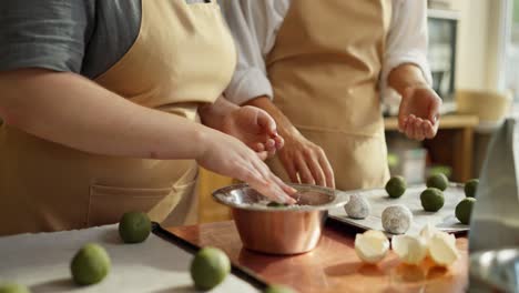 two people baking green cookies together in a kitchen