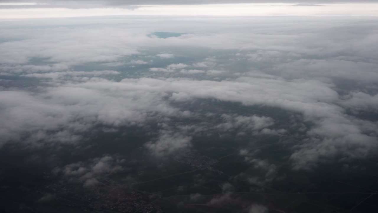 Flying across Germany, the aircraft soars over fog-covered hills beneath heavy overcast. Mist drifts across the rolling terrain, creating a dramatic and atmospheric view of the countryside from above