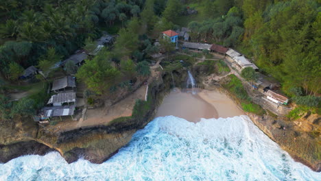 Der-Abgelegene-Strand-Von-Banyu-Tibo-An-Der-Küste-Südjavas-Wird-Von-Wellen-überrollt,-Während-Eine-Drohne-Herabsinkt