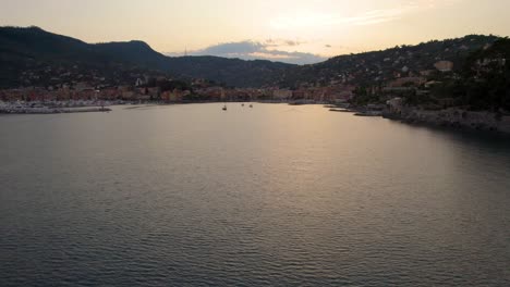 Hermosa-Puesta-De-Sol-Que-Se-Refleja-En-La-Superficie-Del-Océano-En-La-Costa-De-Portofino,-Italia---Vuelo-Aéreo-Que-Establece-Con-Espacio-De-Copia-En-El-Cielo