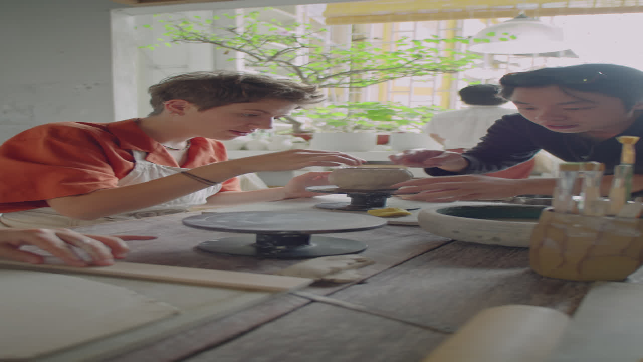 Asian Girl Wetting Clay on Pottery Lesson