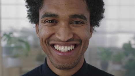 close up portrait of young mixed race man smiling cheerful looking at camera enjoying successful job opportunity ambitious male in office workspace background