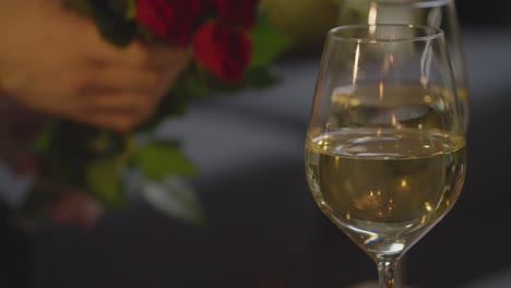 hombre recogiendo un ramo de rosas y vino de la mesa para el romántico día de san valentín en casa