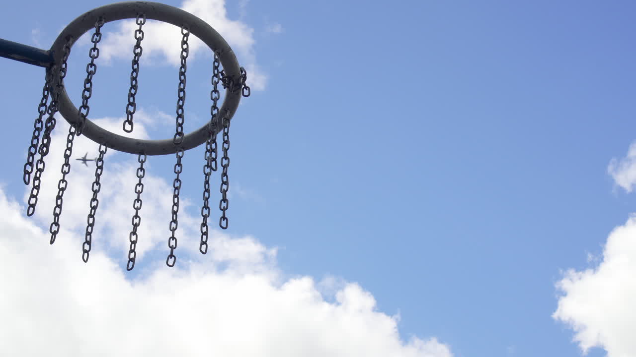 Close up of a Basketball hoop while an airplane is flying by