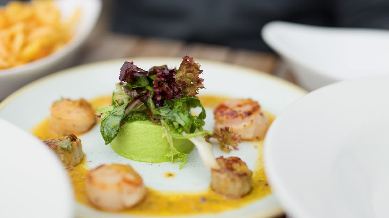 Green pea panna cotta and seared scallops plated in bright, natural restaurant lighting