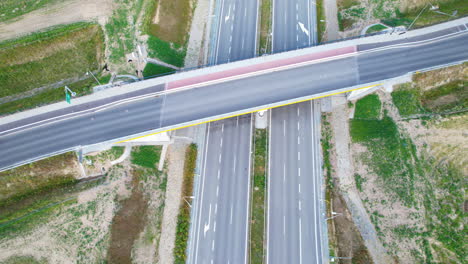 上下傾斜的車輛在橋道上行駛, 穿過一個鄉村空的多車線高速公路, 無交通, 周圍有廣<unk>的田野和土地, 沥青基礎設施