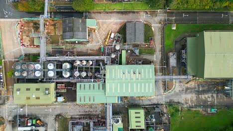 aerial view progresses toward a british chemical plant, displaying pipelines, metal frameworks, cooling towers, and chemical storage