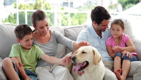 Süße-Familie-Entspannt-Sich-Zusammen-Mit-Ihrem-Labrador-Hund-Auf-Der-Couch