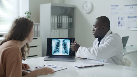 african american doctor explaining chest x-ray on laptop to patient