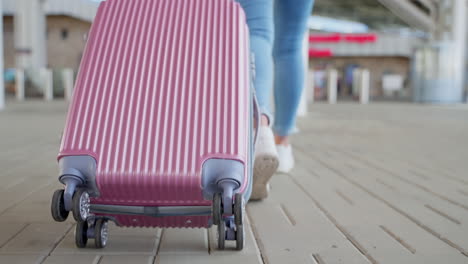 woman with a pink suitcase at the airport/train station