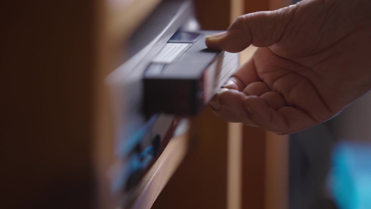 VHS cassette ejects from player revealing broken tape, close up, indoor setting
